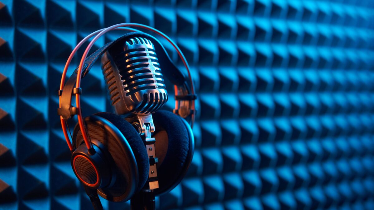 Fondo acústico atrapa sonido, con unos audfinos profesionales encima de un micrófono, consejos para podcast