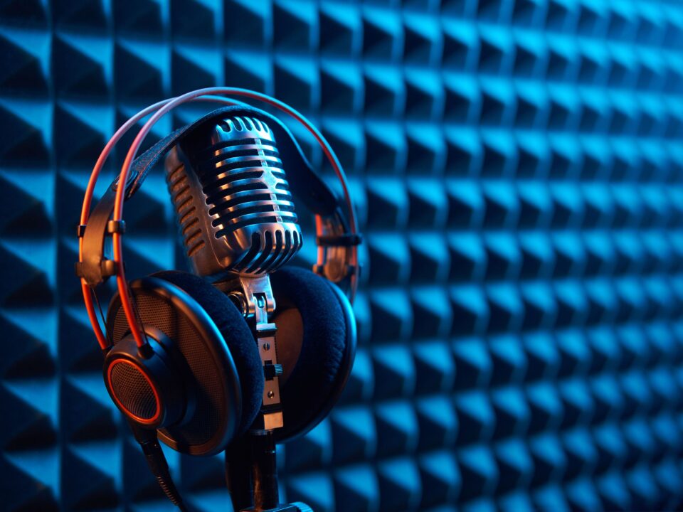 Fondo acústico atrapa sonido, con unos audfinos profesionales encima de un micrófono, consejos para podcast