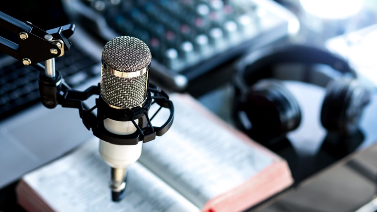 Set para un pódcast con un micrófono, audífonos y una Biblia, podcast en español