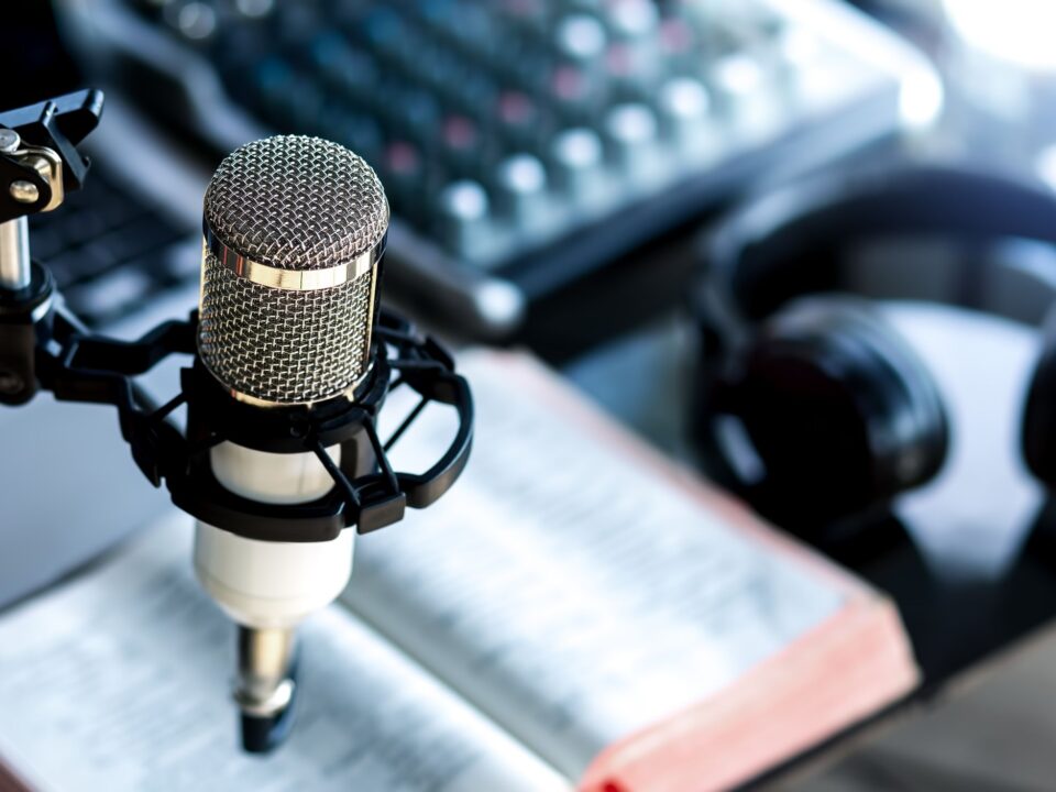 Set para un pódcast con un micrófono, audífonos y una Biblia, podcast en español